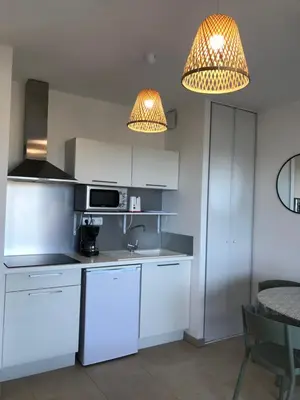a kitchen with white cabinets and a sink and two lights at marina di bravone 185 vue mer in Linguizzetta