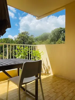 a table and chair on a balcony with a view at Appartement l'orée du bois Ajaccio in Ajaccio
