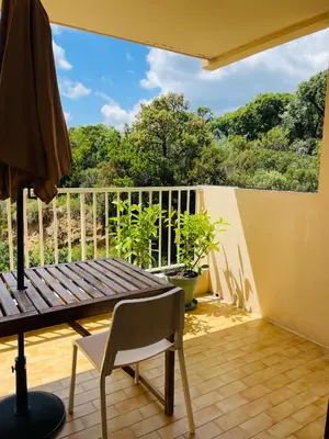 a balcony with a wooden table and a chair at Appartement l'orée du bois Ajaccio in Ajaccio
