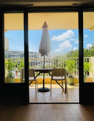 a table with an umbrella and two chairs on a balcony at Appartement l'orée du bois Ajaccio in Ajaccio