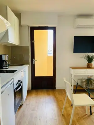 a kitchen with a door and a table and a chair at Appartement l'orée du bois Ajaccio in Ajaccio