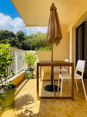 a table and an umbrella on a balcony at Appartement l'orée du bois Ajaccio in Ajaccio