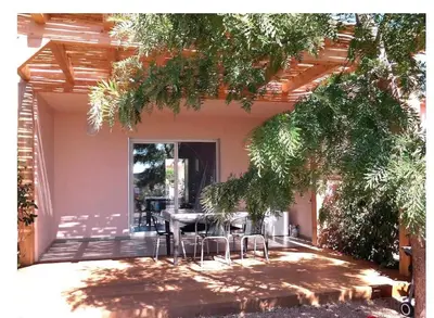 a patio with a table and chairs in front of a house at Appart, piscine, proche plage in Lecci