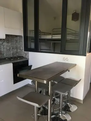 a kitchen with a table and two bar stools at Appart, piscine, proche plage in Lecci