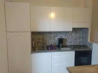 a kitchen with white cabinets and a sink at Appart, piscine, proche plage in Lecci