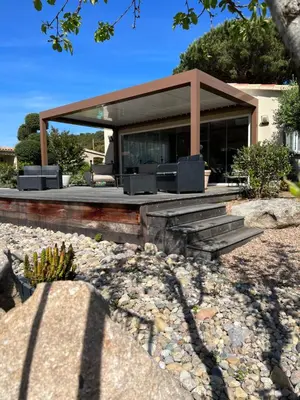 a house with a porch with two chairs on it at Hotel les jardins Sta Giulia avec piscine in Porto-Vecchio