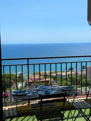 a table on a balcony with a view of the ocean at VUE MER EXCEPTIONNELLE !! Studio calme et lumineux sur la prestigieuse route des Sanguinaires à Ajaccio in Ajaccio
