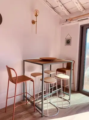 a table and stools in a room with a window at Duplex pour 2 à 6 personnes avec terrasse en plein cœur de la citadelle de Bonifacio in Bonifacio