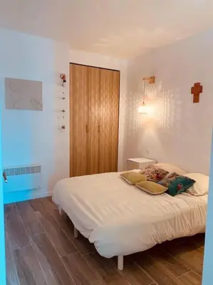 a bedroom with a white bed with a wooden cabinet at Duplex pour 2 à 6 personnes avec terrasse en plein cœur de la citadelle de Bonifacio in Bonifacio