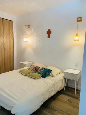a bedroom with a bed with two pillows and a cross on the wall at Duplex pour 2 à 6 personnes avec terrasse en plein cœur de la citadelle de Bonifacio in Bonifacio