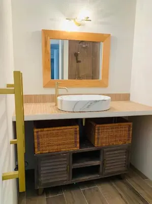 a bathroom with a sink with a mirror and baskets at Duplex pour 2 à 6 personnes avec terrasse en plein cœur de la citadelle de Bonifacio in Bonifacio