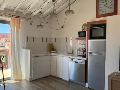 a kitchen with white appliances and a clock on the wall at Duplex pour 2 à 6 personnes avec terrasse en plein cœur de la citadelle de Bonifacio in Bonifacio