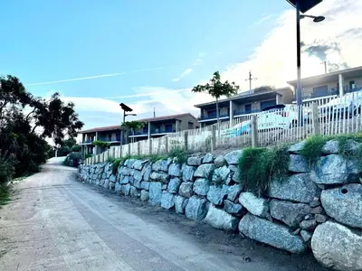 a stone wall next to a road with houses at Appartement Tour d'Omigna Cargèse in Cargèse