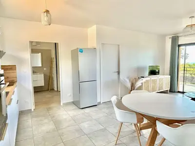 a kitchen and dining room with a table and a refrigerator at Appartement Tour d'Omigna Cargèse in Cargèse