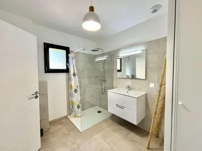 a white bathroom with a shower and a sink at Appartement Tour d'Omigna Cargèse in Cargèse