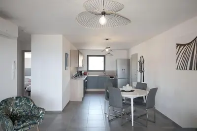 a dining room and kitchen with a table and chairs at Appartement récent, tout confort , vue mer, plage à 5min in Propriano