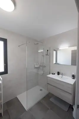 a white bathroom with a shower and a sink at Appartement récent, tout confort , vue mer, plage à 5min in Propriano