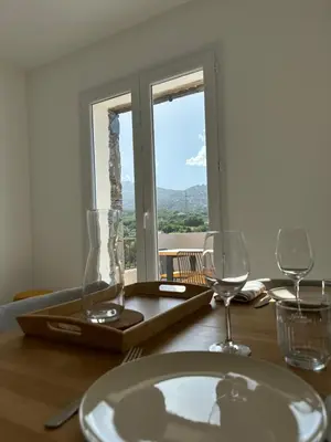a table with a plate and two wine glasses at Bergerie avec spa vue montagne in San-Nicolao
