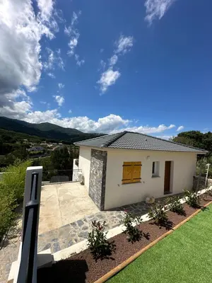 a small white house with a grass yard at Bergerie avec spa vue montagne in San-Nicolao