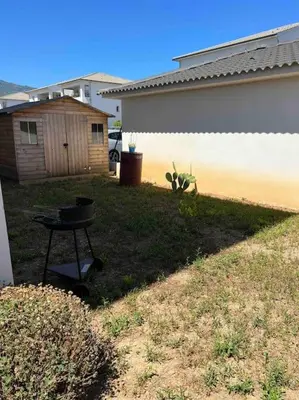 a grill in a yard next to a house at Appartement T2 avec jardin in Lucciana