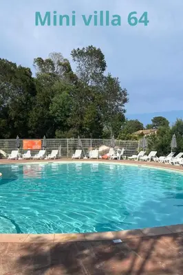 a swimming pool with blue water and lounge chairs at Mini Villa 63 proche plage dans résidence avec piscine à Favone in Sari Solenzara