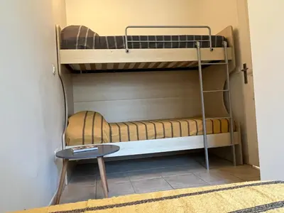 a room with two bunk beds and a table at Mini Villa 63 proche plage dans résidence avec piscine à Favone in Sari Solenzara