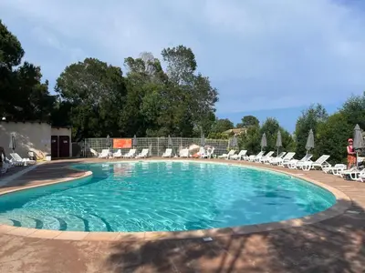 a large swimming pool with chairs at Mini Villa 63 proche plage dans résidence avec piscine à Favone in Sari Solenzara