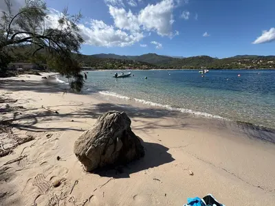 a rock sitting on a beach with a rock in the sand at Mini Villa 63 proche plage dans résidence avec piscine à Favone in Sari Solenzara
