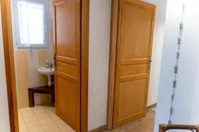 a bathroom with a wooden door and a sink at Villa Tizzano Vue Mer in Sartène
