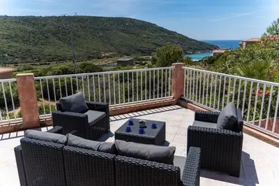 a patio with chairs and a table on a balcony at Villa Tizzano Vue Mer in Sartène