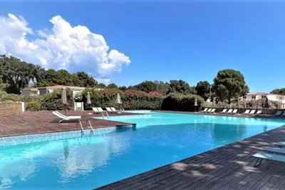 a large swimming pool with blue water and lounge chairs at T2 Neuf à 800 m de la plage de Cala Rossa appart n 80 in Lecci