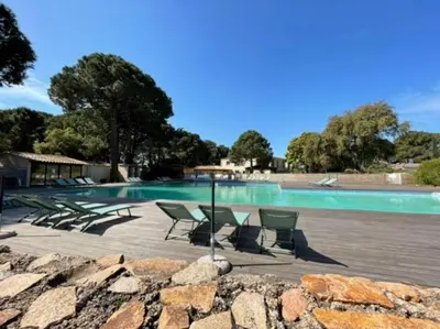 a swimming pool with chairs and a group of trees at T2 Neuf à 800 m de la plage de Cala Rossa appart n 80 in Lecci