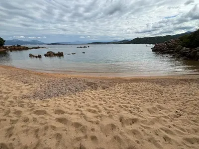 a sandy beach with rocks in the water at La vie en rose in Coti-Chiavari
