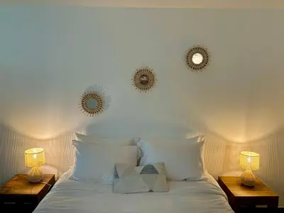 a white bed with two mirrors on the wall at La vie en rose in Coti-Chiavari
