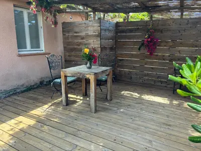 a wooden table with a vase of flowers on a patio at La vie en rose in Coti-Chiavari