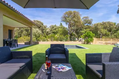 a patio with two chairs and a table and an umbrella at Casa Omigna in Figari
