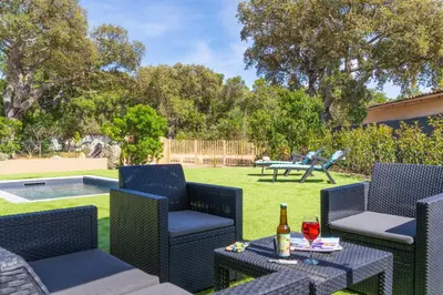 a patio with chairs and a table with a bottle of wine at Casa Omigna in Figari