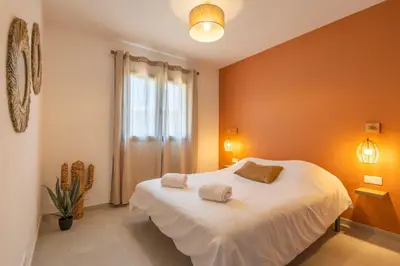 a bedroom with a large white bed with orange walls at Casa Omigna in Figari