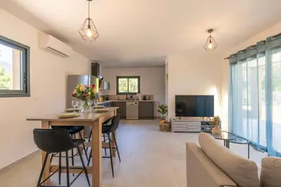 a kitchen and living room with a table and chairs at Casa Omigna in Figari