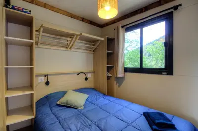 a bedroom with a blue bed and a window at CHALET U Castagnu in Venaco