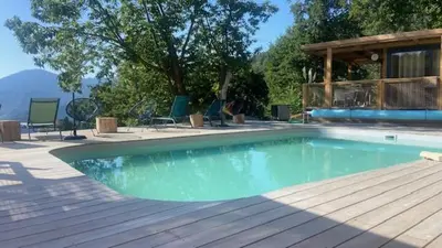 a swimming pool with chairs and a wooden deck at CHALET U Castagnu in Venaco