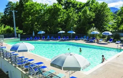 a swimming pool with blue chairs and umbrellas at Appartement T3 bord de mer résidence Aqualinda E55 in Poggio-Mezzana