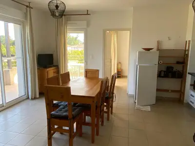 a dining room with a table and chairs and a refrigerator at Appartement T3 bord de mer résidence Aqualinda E55 in Poggio-Mezzana