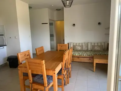 a dining room with a table and chairs and a couch at Appartement T3 bord de mer résidence Aqualinda E55 in Poggio-Mezzana