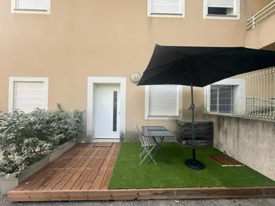 a patio with a table and an umbrella in front of a house at T2 bord de mer in Albitreccia