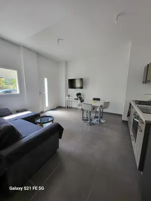 a living room with a black couch and a kitchen at T2 bord de mer in Albitreccia