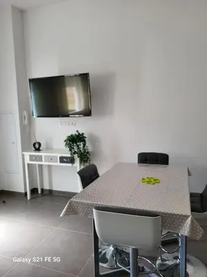 a dining room with a table with chairs and a flat screen tv at T2 bord de mer in Albitreccia