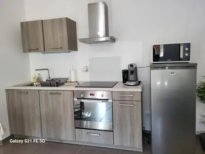 a kitchen with a stainless steel stove and a refrigerator at T2 bord de mer in Albitreccia