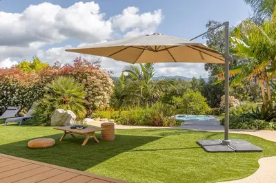 an umbrella in a yard with a bench and a table at Maison O Ciucciarella - Climatisée avec jacuzzi in Grosseto-Prugna
