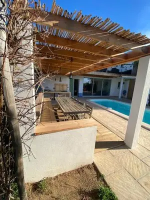a patio with a wooden pergola next to a pool at Villa bord de mer avec piscine 200 métres plage in Zonza